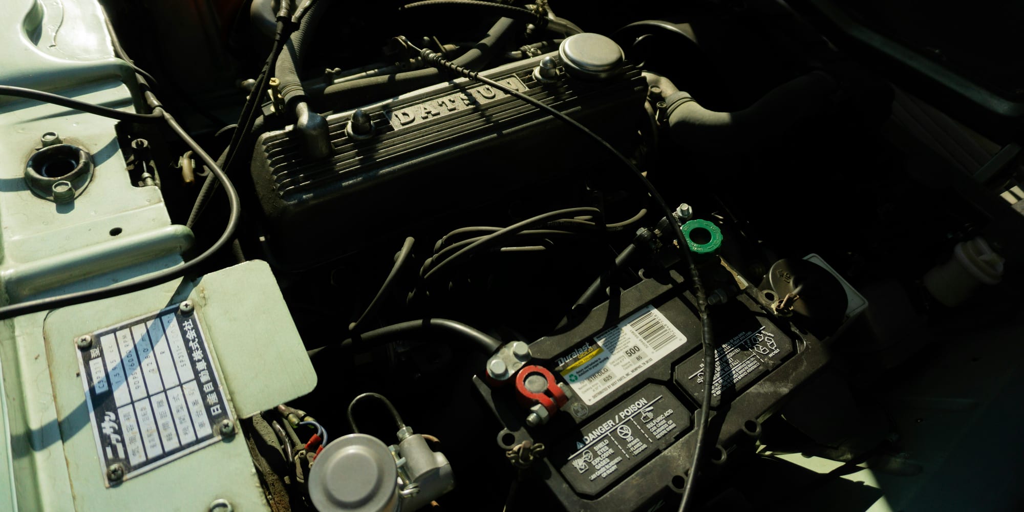 A car battery mounted in the engine bay of an older vehicle