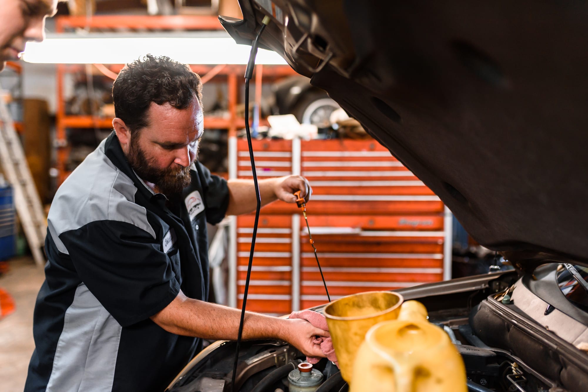 An ASE-certified technician adding oil to an engine at Master Team Automotive